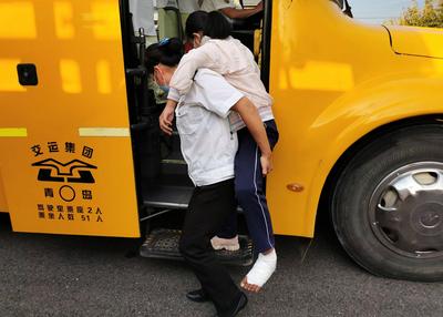 青岛校园里有道温馨风景：学生脚伤行走不便，校车照管员背着上下学