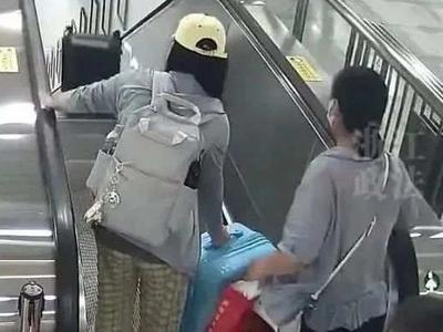 危险！一女子用扶梯传送行李箱，砸伤路人